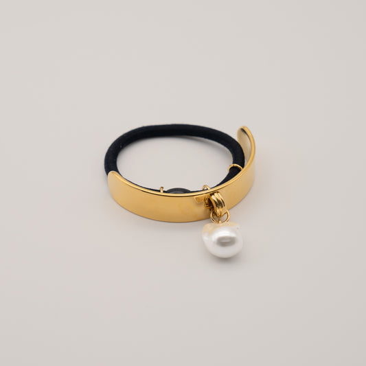 Flat lay of Rosy Collective gold ponytail hair cuff with a freshwater pearl hair accessories