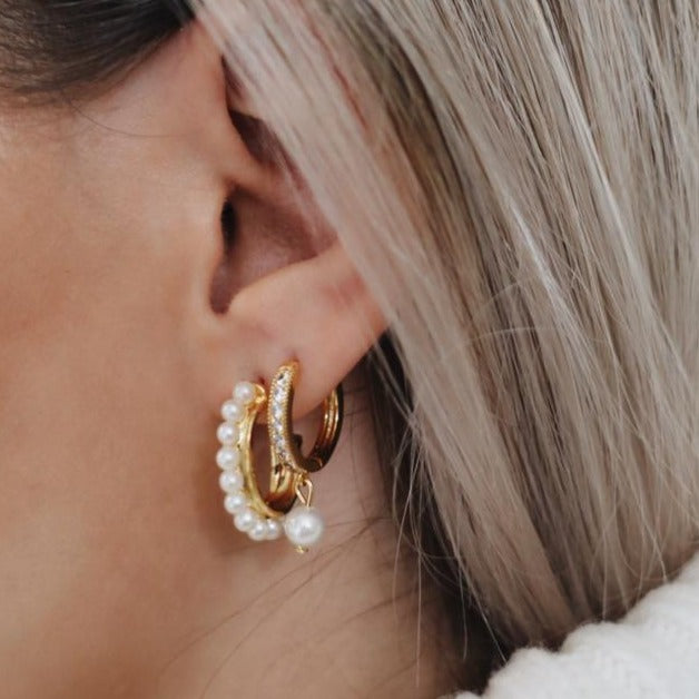 blonde model close up of her ear wearing two pearl hoop earrings