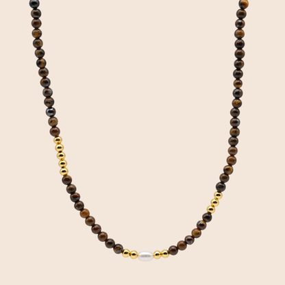 Necklace with brown beads and a gold accent on a beige background