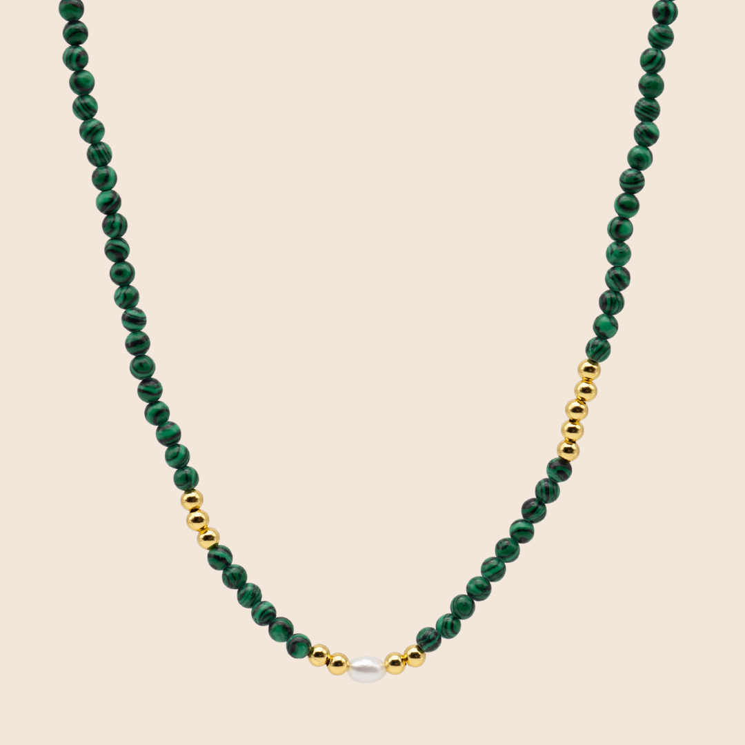 Necklace with green beads and gold accents on a beige background
