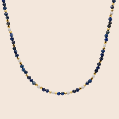 Necklace with blue, white, and gold beads on a beige background