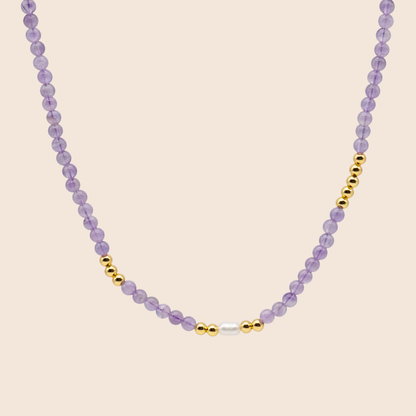 Necklace with purple beads and gold accents on a beige background