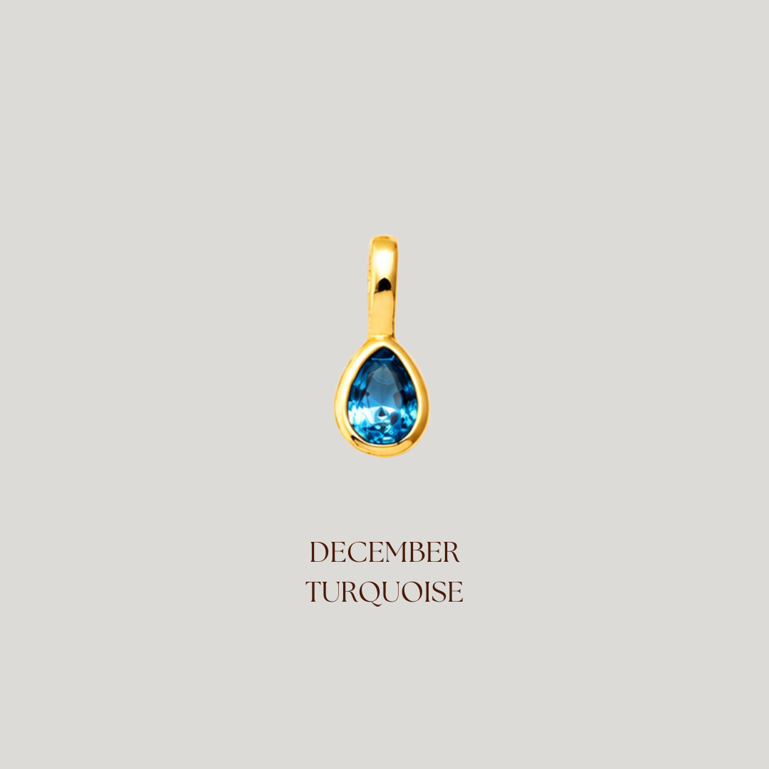 Gold pendant with a blue gemstone on a light gray background