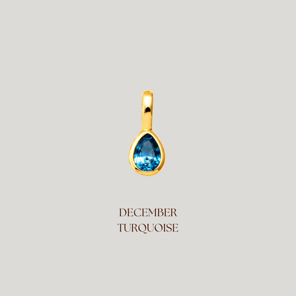 Gold pendant with a blue gemstone on a light gray background