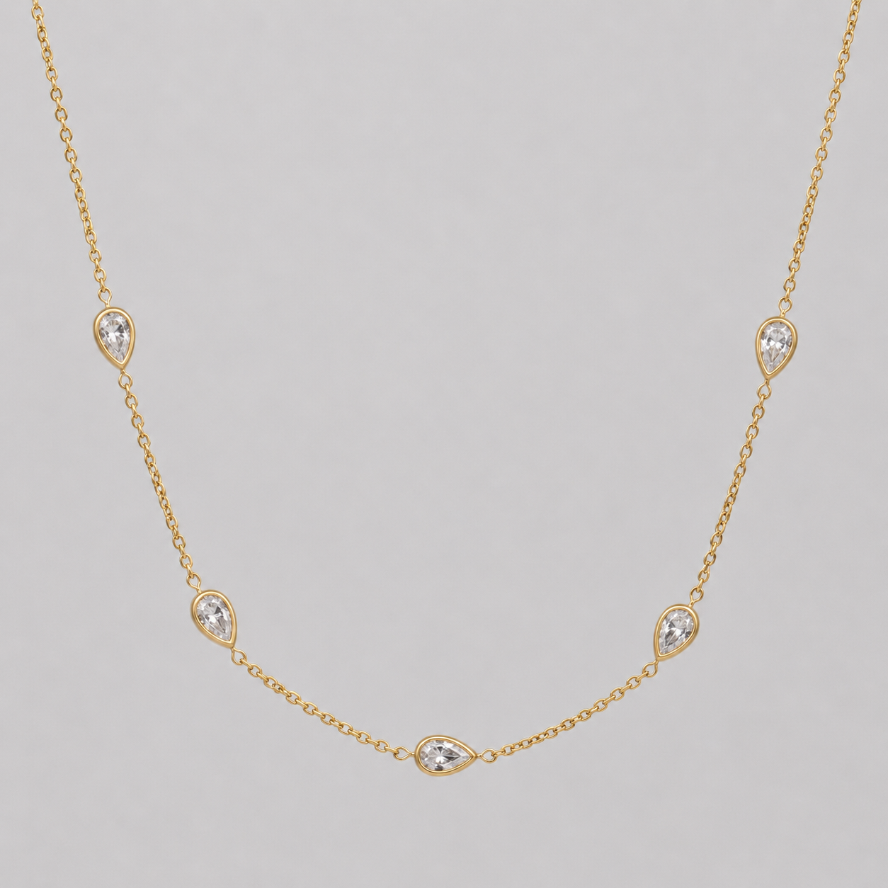 Gold necklace with diamond-like stones on a gray background