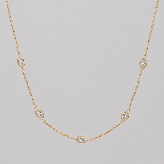 Gold necklace with diamond-like stones on a gray background