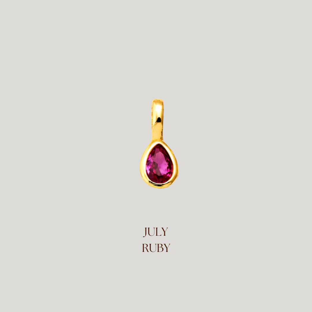 Gold pendant with a red gemstone on a light gray background, labeled 'July Ruby'.