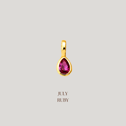 Gold pendant with a red gemstone on a light gray background, labeled 'July Ruby'.