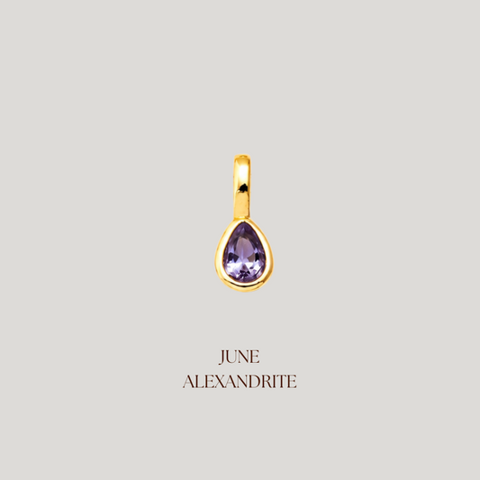 Gold pendant with a purple gemstone on a light gray background