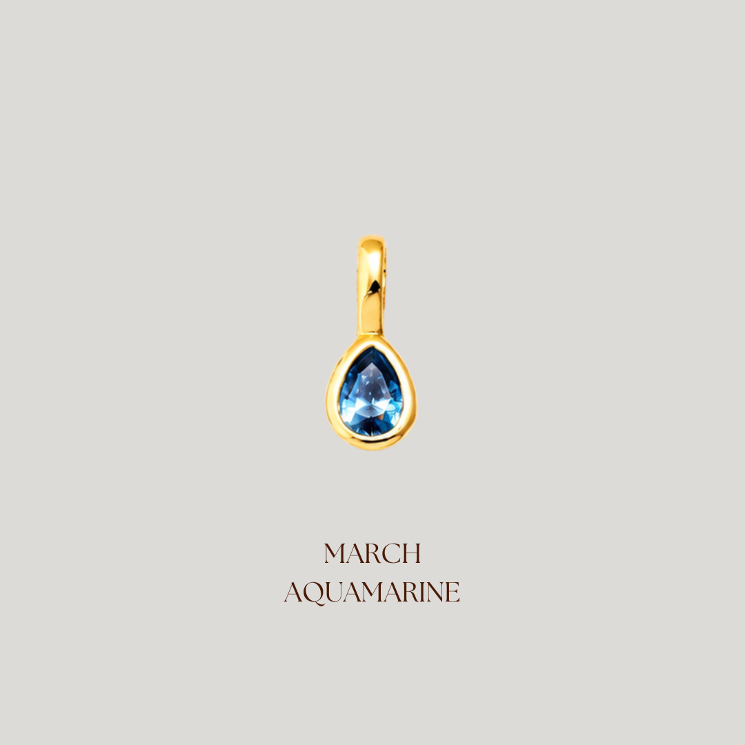 Gold pendant with a blue gemstone on a light gray background