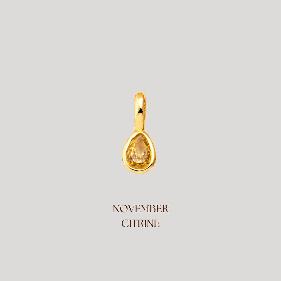 Gold teardrop pendant with a yellow gemstone on a light gray background, labeled 'November Citrine'.