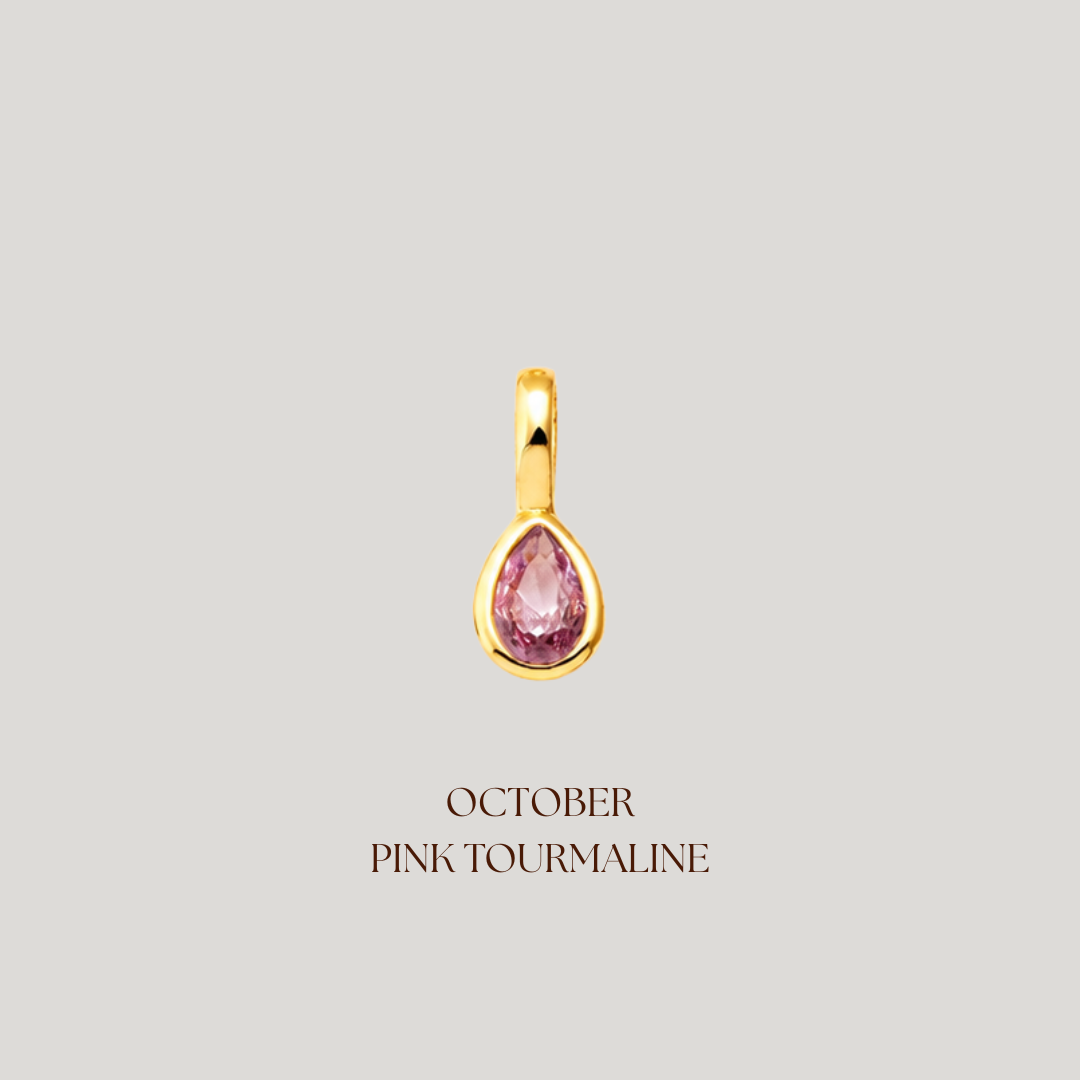 Gold pendant with pink gemstone on a light gray background