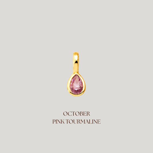 Gold pendant with pink gemstone on a light gray background