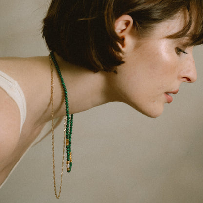 Woman wearing a green beaded necklace against a neutral background