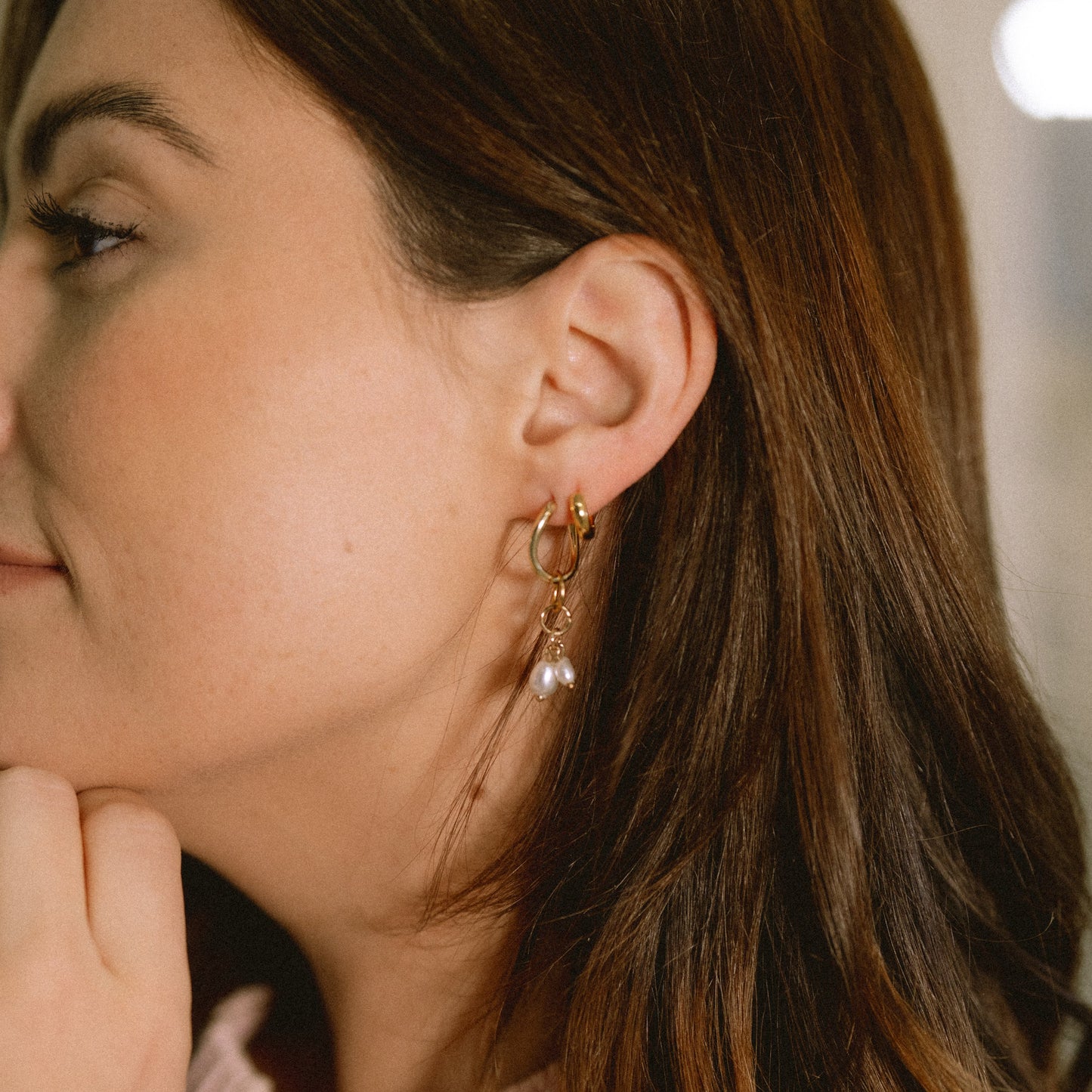 Woman wearing pearl earrings with a soft focus background