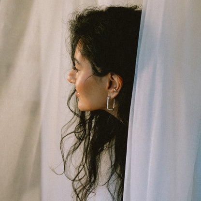 Woman peeking through sheer curtains with a soft focus