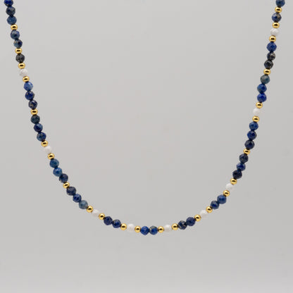 Necklace with blue, gold, and white beads on a gray background