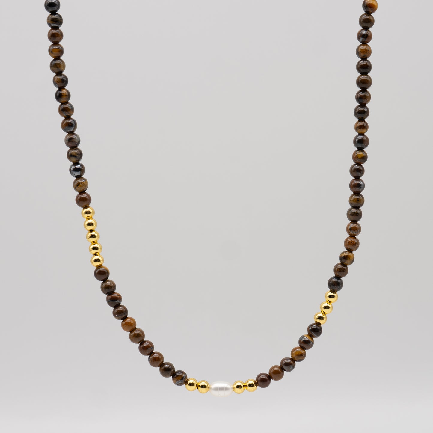 Necklace with brown beads and gold accents on a gray background