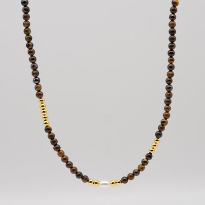 Necklace with brown beads and gold accents on a gray background