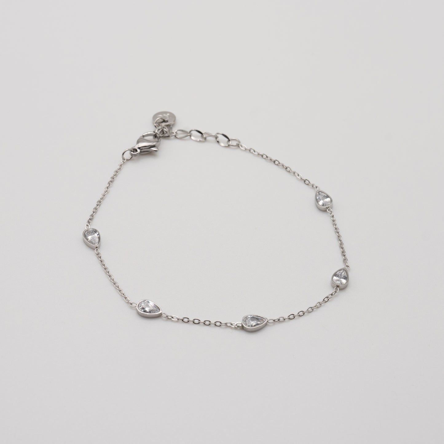Silver bracelet with teardrop-shaped charms on a light gray background