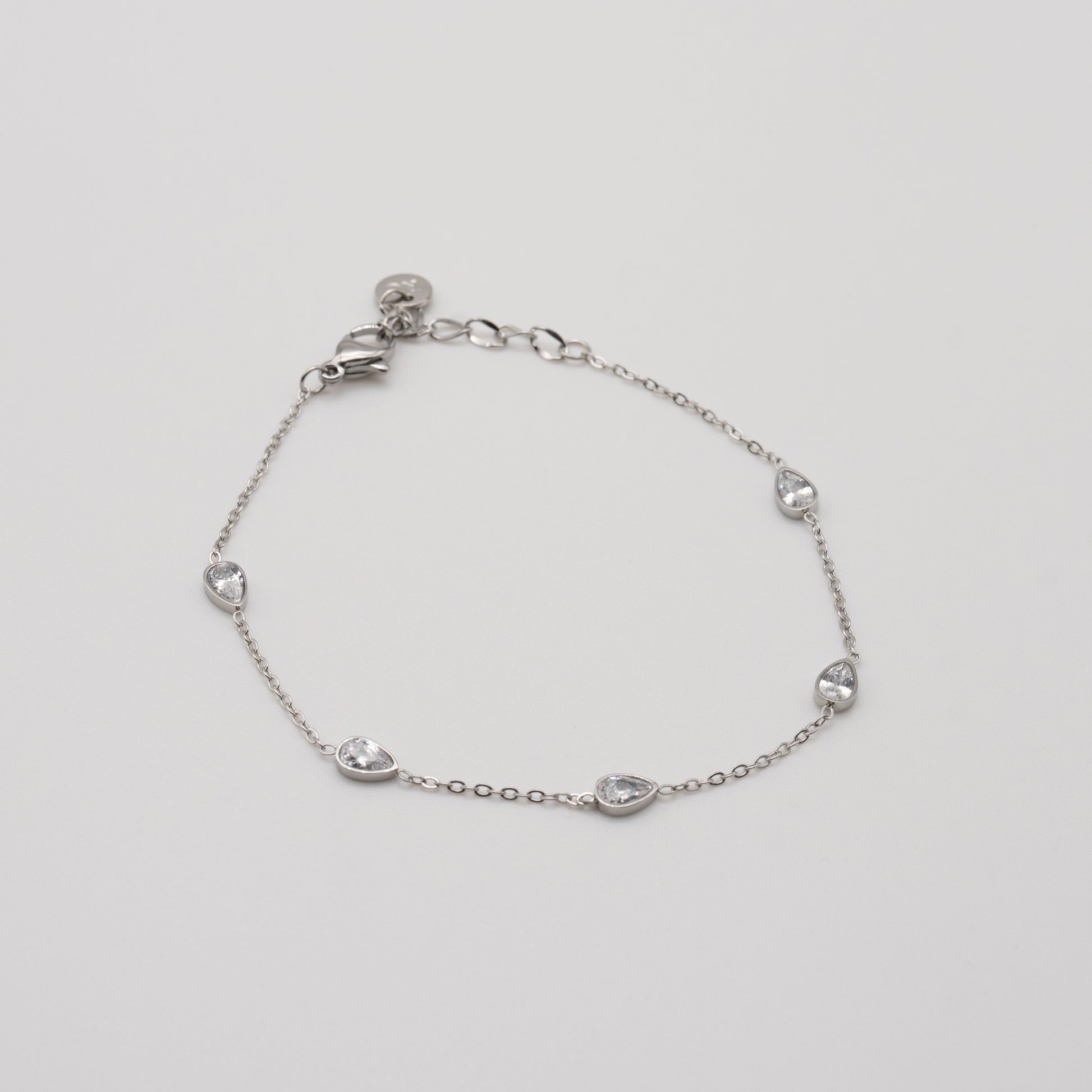 Silver bracelet with teardrop-shaped charms on a light gray background