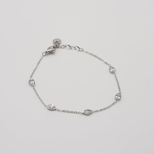 Silver bracelet with teardrop-shaped charms on a light gray background