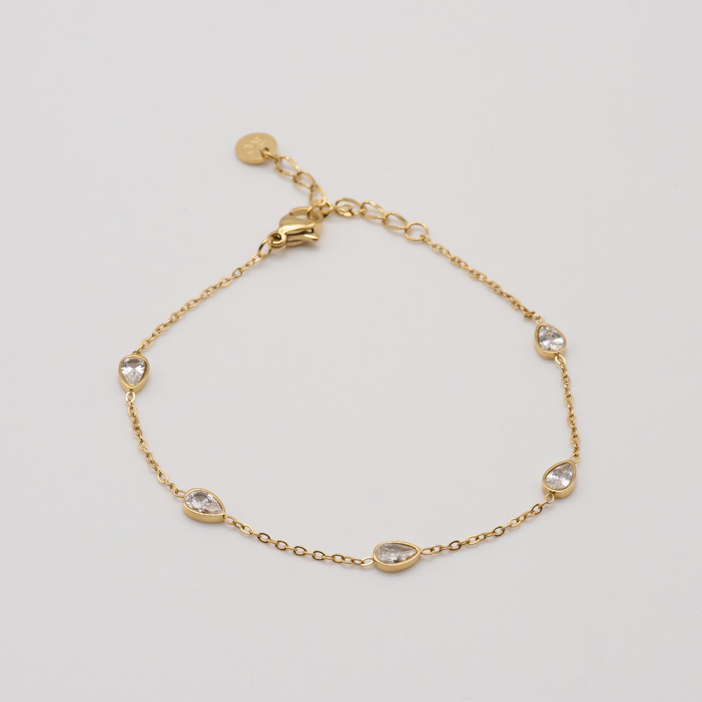 Gold bracelet with small crystals on a light gray background