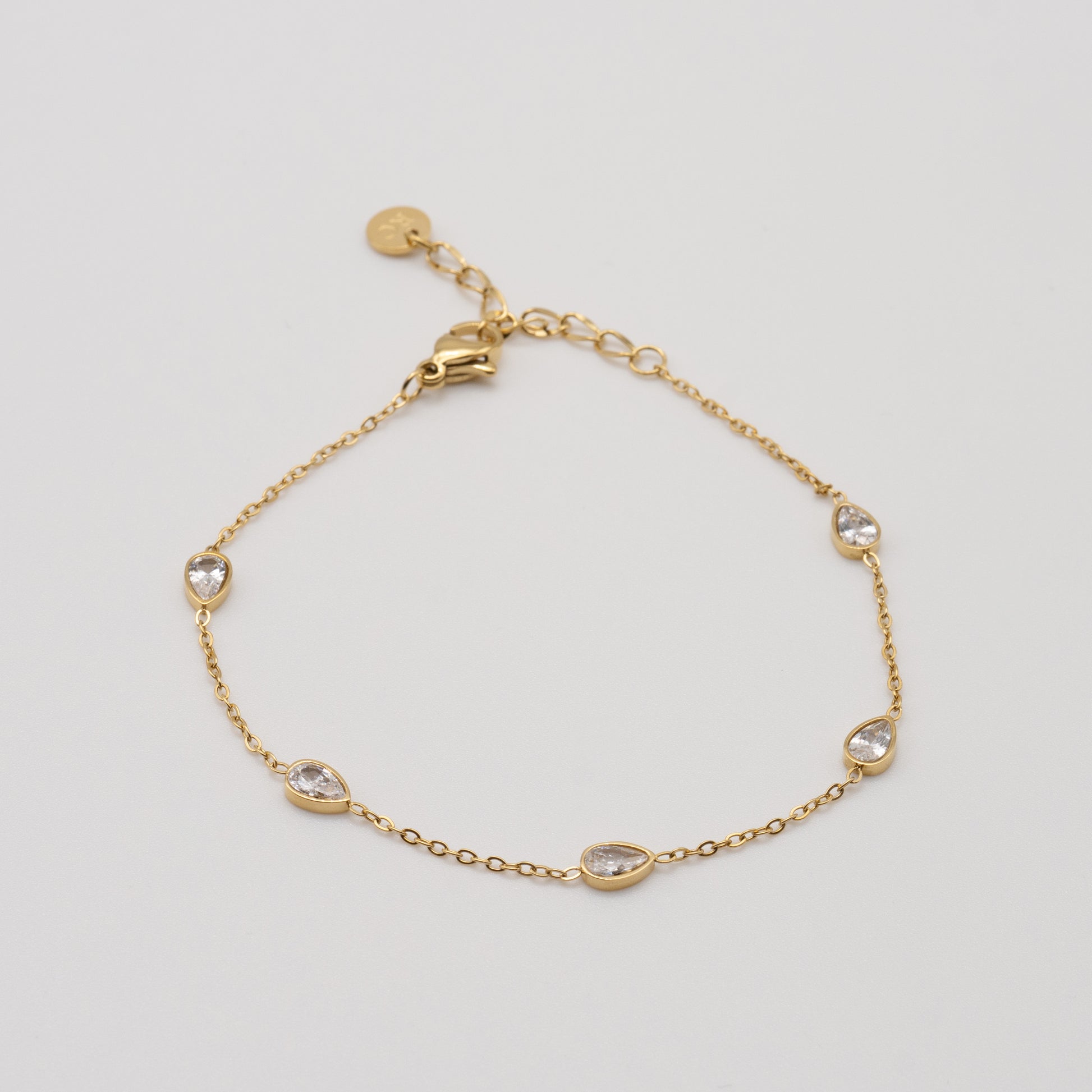 Gold bracelet with small crystals on a light gray background