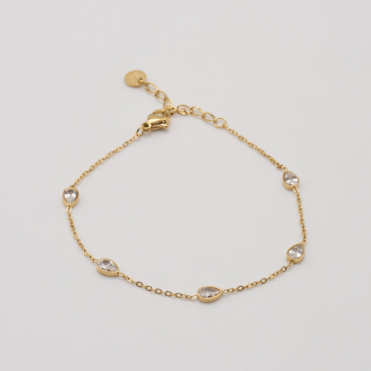 Gold bracelet with small crystals on a light gray background