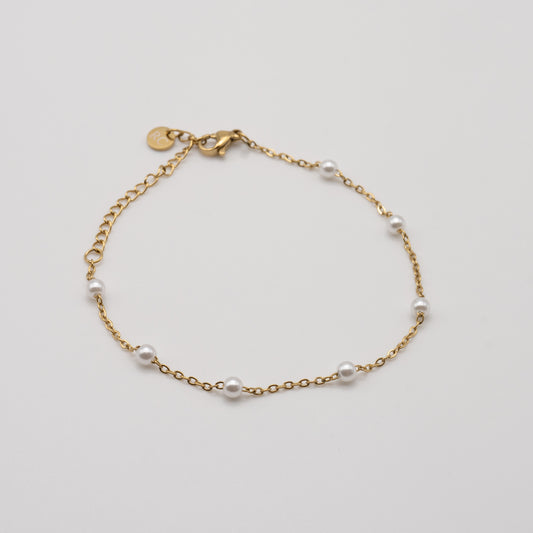 Gold bracelet with pearls on a light gray background