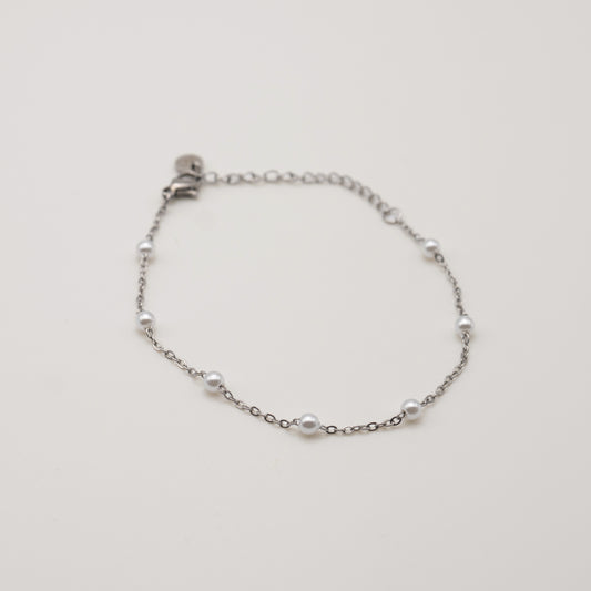 Silver bracelet with pearls on a light gray background