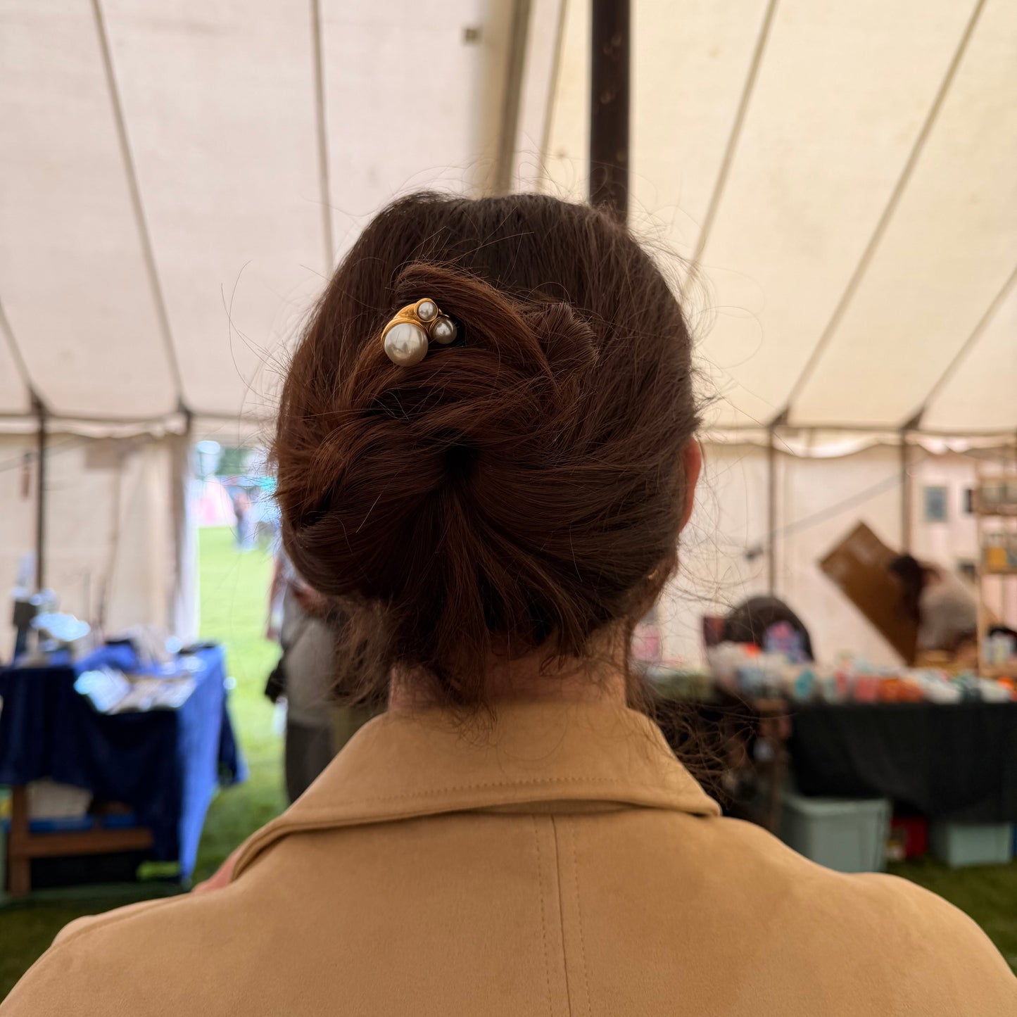 Person wearing a beige coat with a pearl hair pin