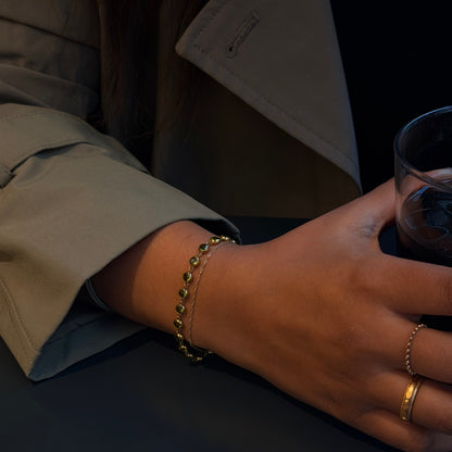 Close-up of a hand wearing gold bracelets and rings on a dark background