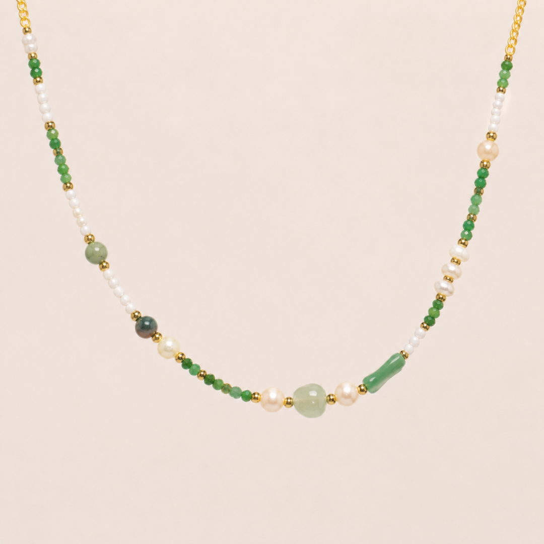 Necklace with green, white, and gold beads on a beige background