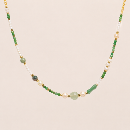 Necklace with green, white, and gold beads on a beige background