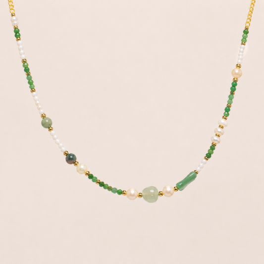 Necklace with green, white, and gold beads on a beige background