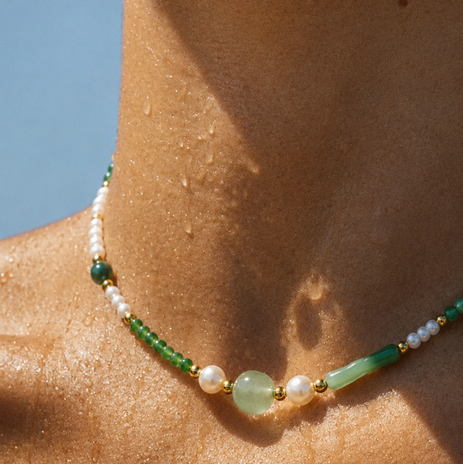 Necklace with green and white beads on a person's neck against a blue sky.