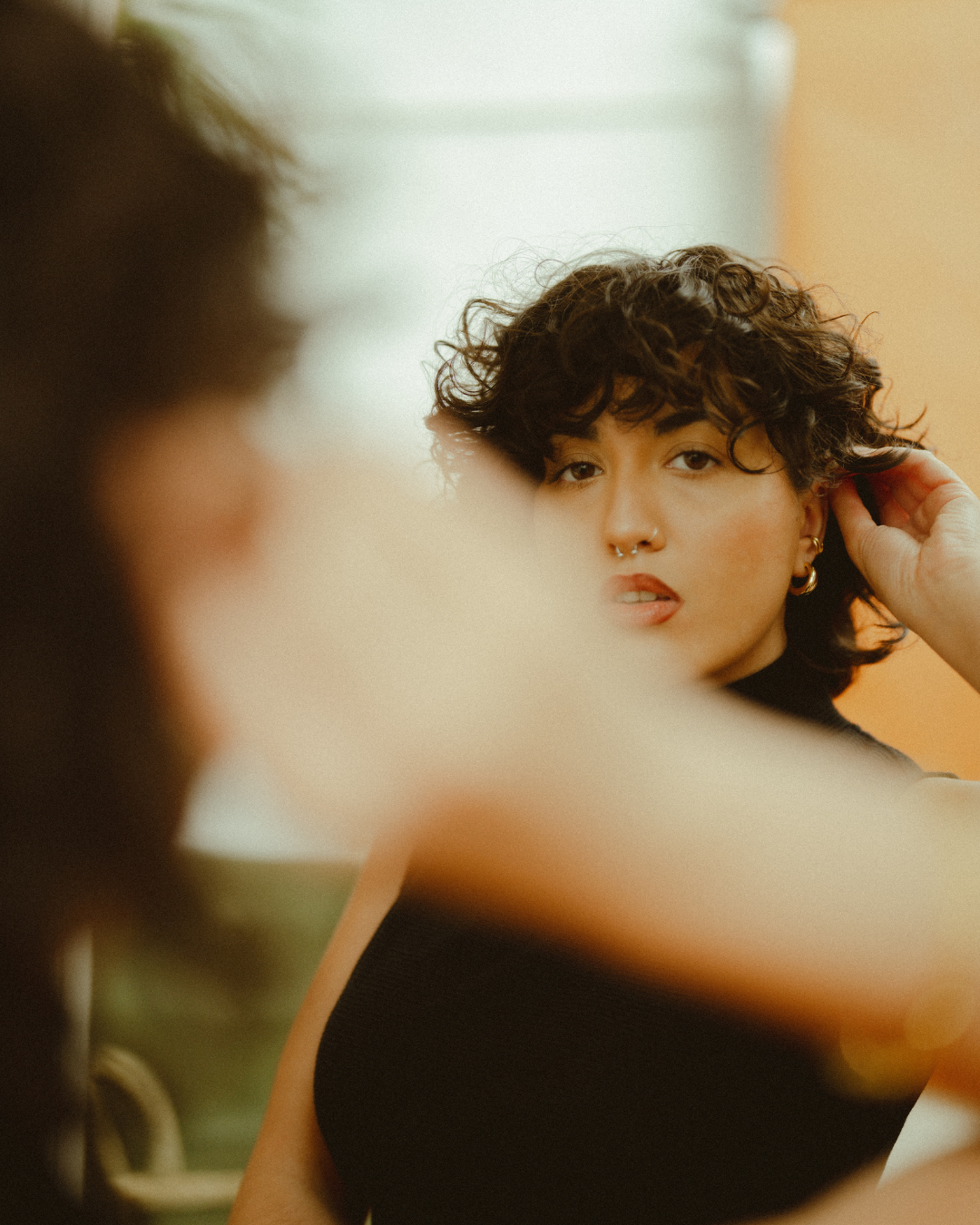 Woman adjusting her hair in a mirror with a blurred foreground